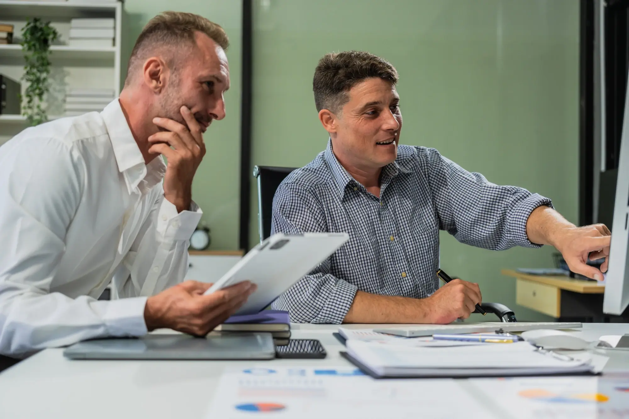 Colleagues reviewing performance charts on a desktop monitor